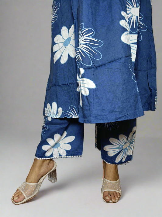Person wearing a blue floral outfit standing against a plain wall.