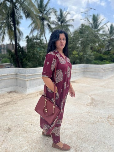 Woman in a patterned dress standing on a rooftop with palm trees in the background