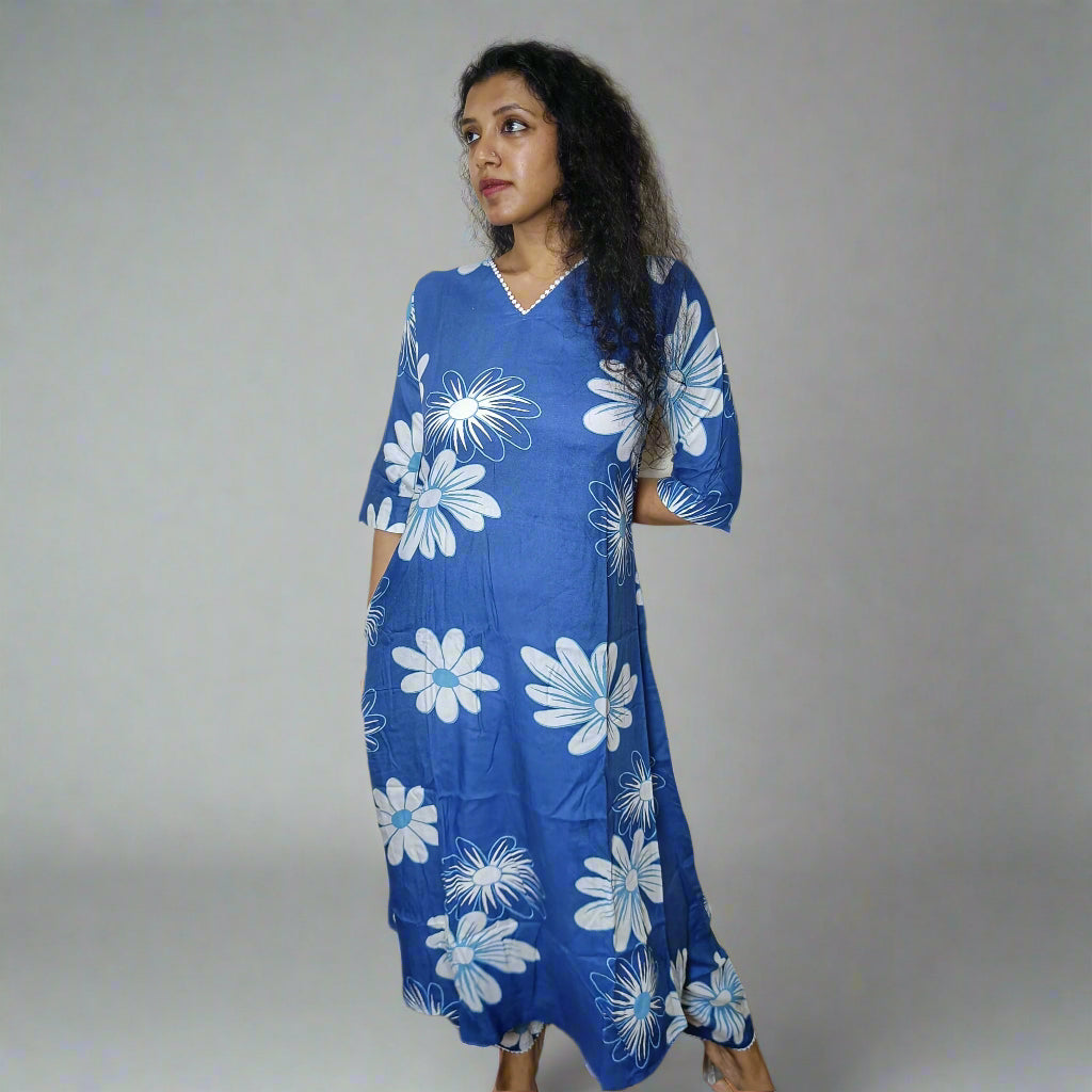 Woman wearing a blue dress with white floral patterns against a plain background