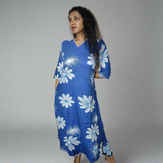 Woman wearing a blue dress with white floral patterns against a plain background